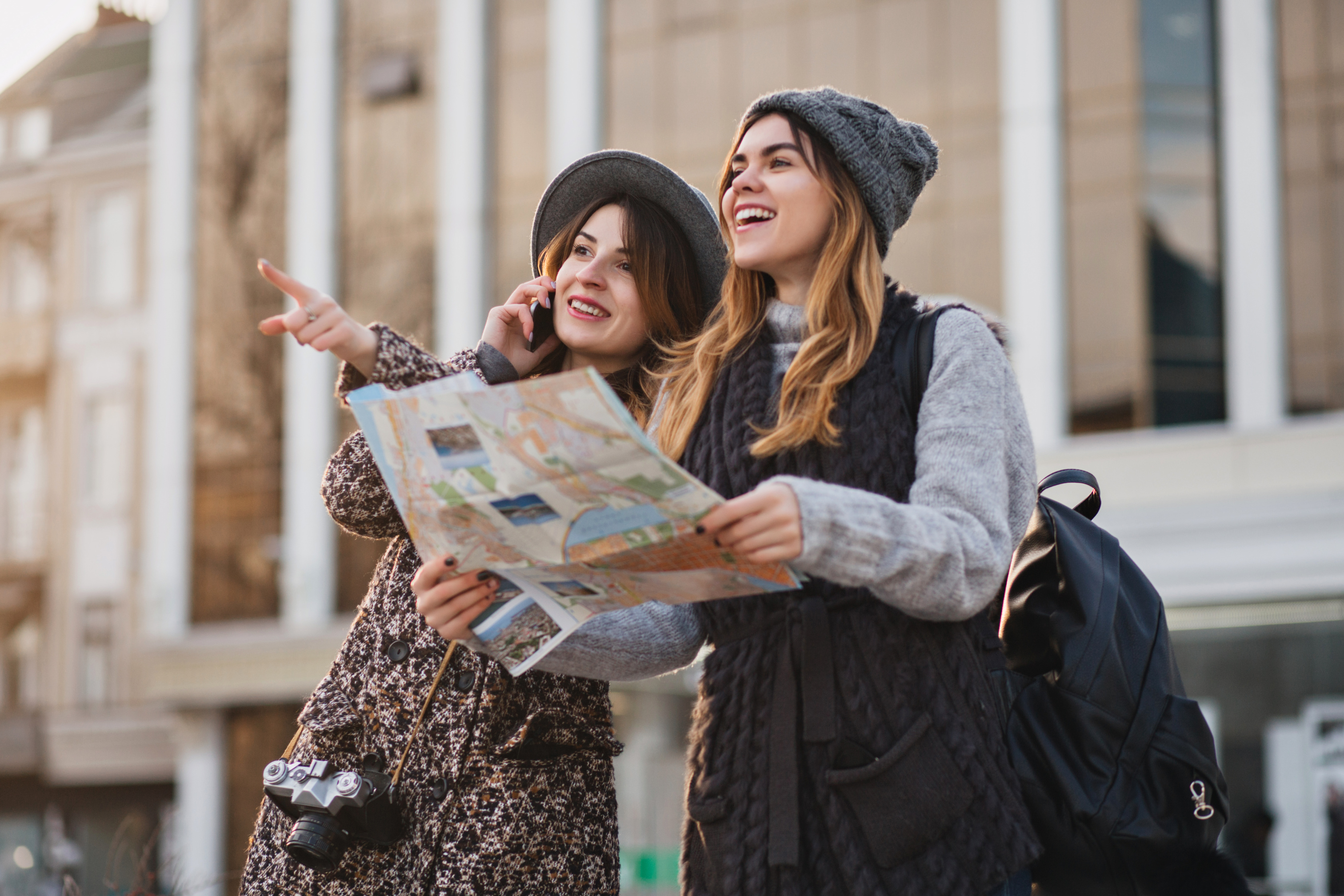 happy-travel-together-of-two-fashionable-women-in-sunny-city-centre-young-joyful-women-expressing-positivity-using-map-vacation-with-bags-cheerful-emotions-good-day.jpg